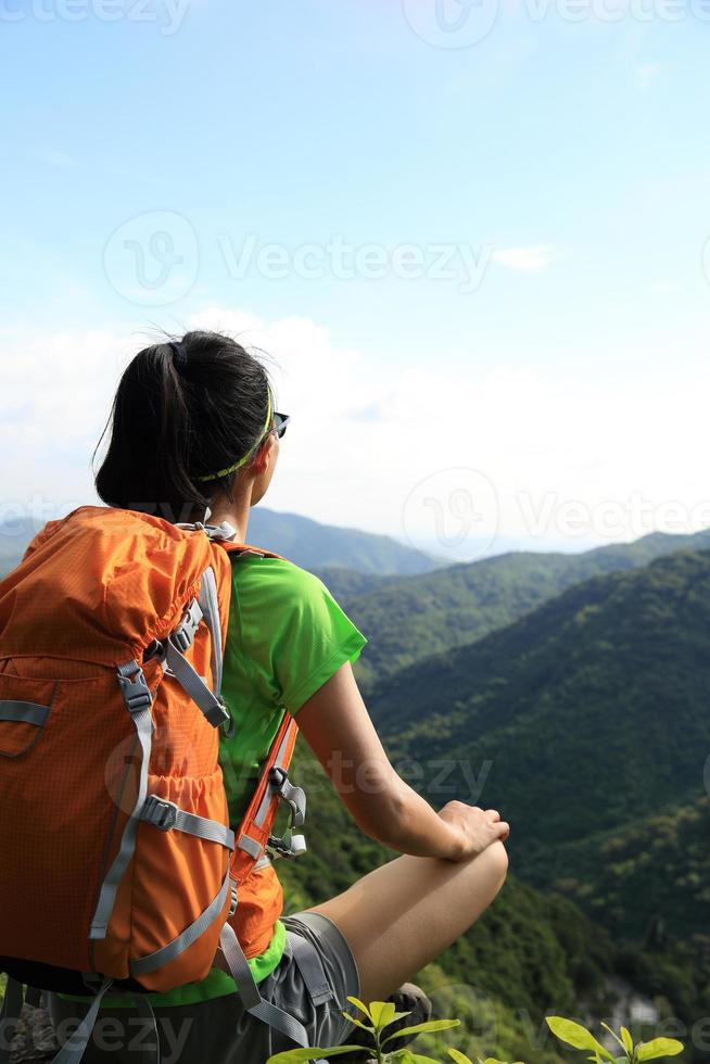 vrouw backpacker geniet van het uitzicht op de bergtop klif foto