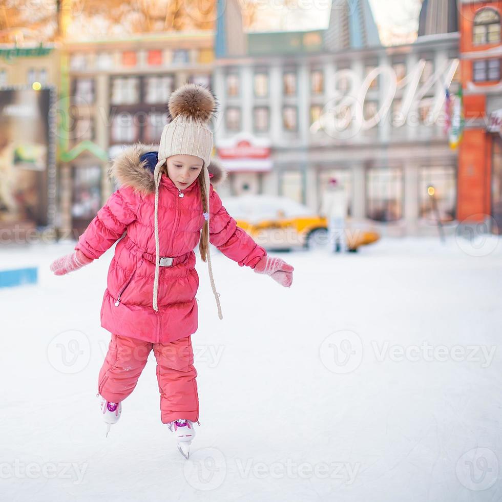 schattig gelukkig meisje genieten van schaatsen op de ijsbaan foto