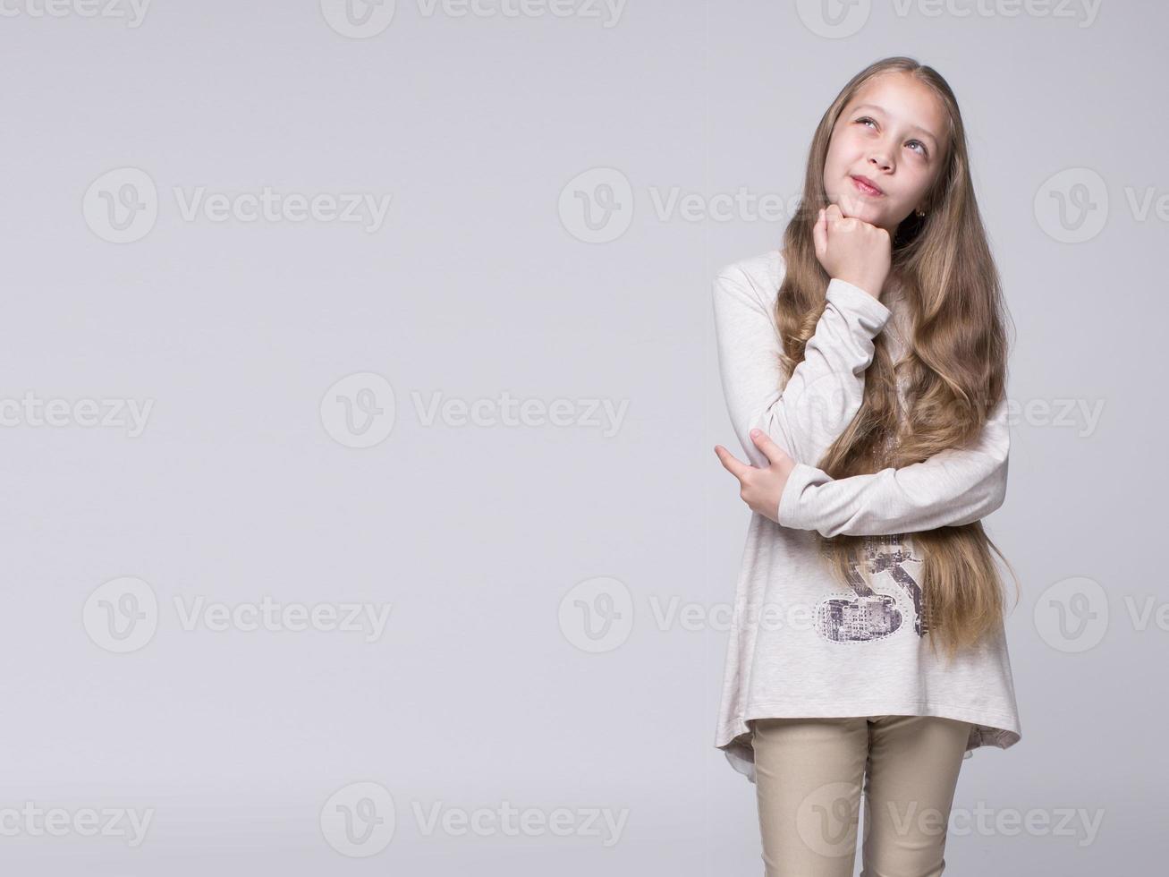 portret van verbijsterd tienermeisje staande op een grijze achtergrond foto