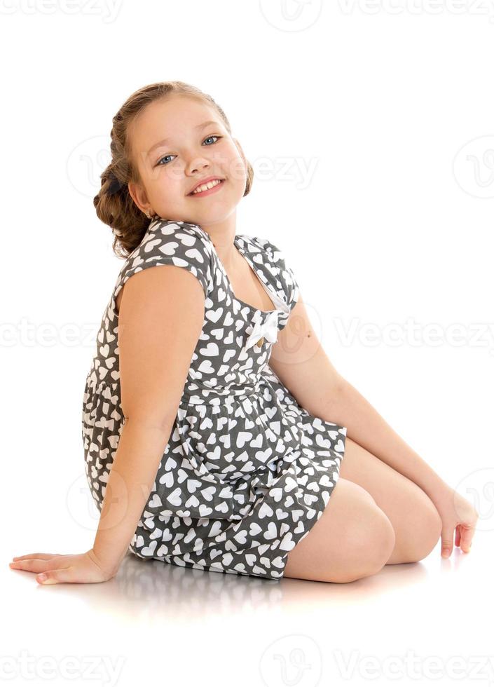vrolijk meisje in zomerjurk zittend op de vloer foto