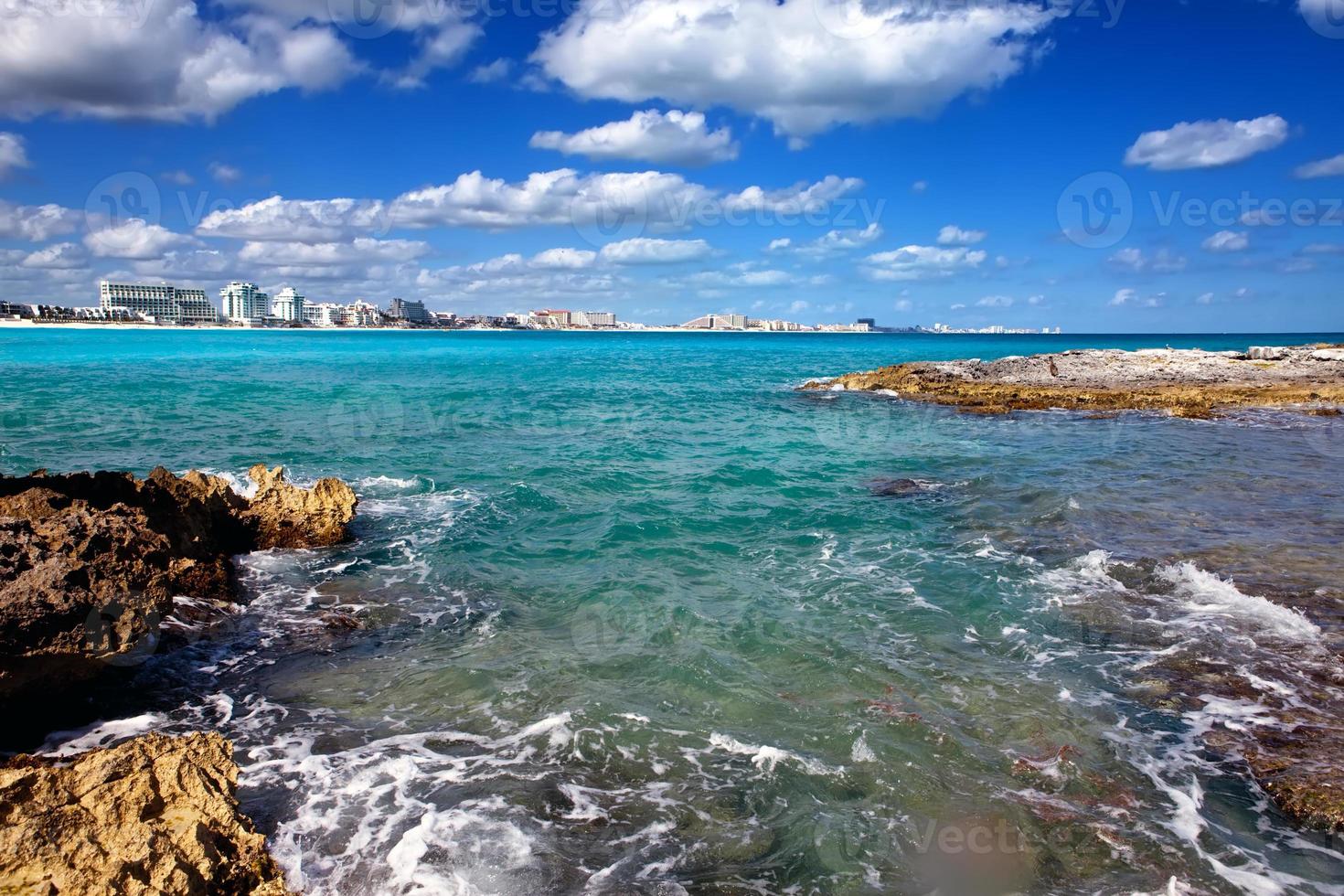rotsachtige kust, zee en stad in de verte mexico. Cancun foto