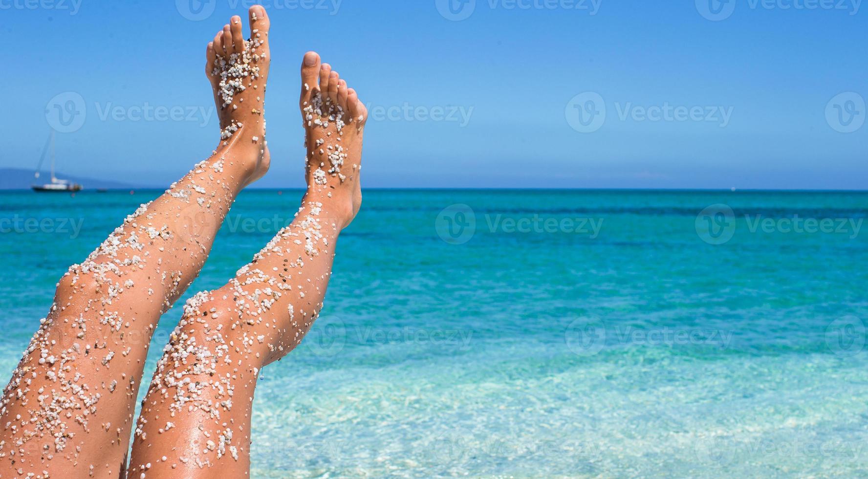 close-up van vrouwelijke benen achtergrond van de turquoise zee foto
