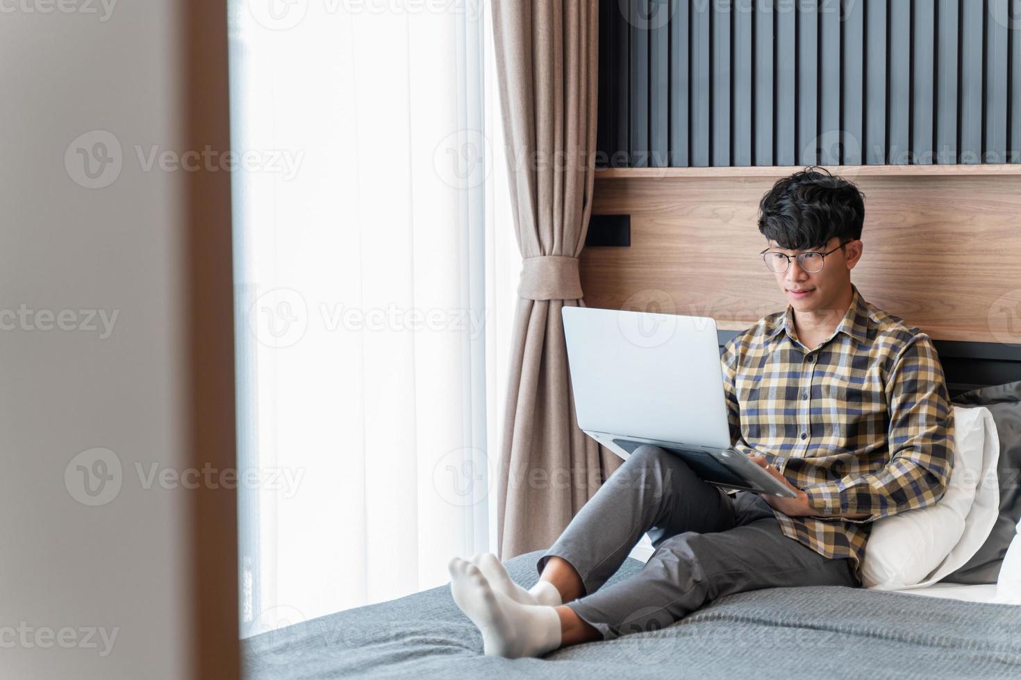 een mannelijke freelancer die tijd doorbrengt met zijn laptops rustig op zijn bed te werken foto