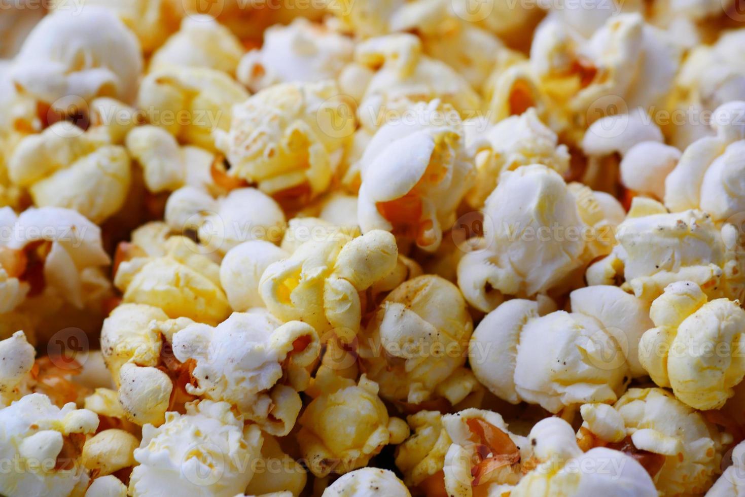 popcorn morsen uit een container op rode achtergrond foto