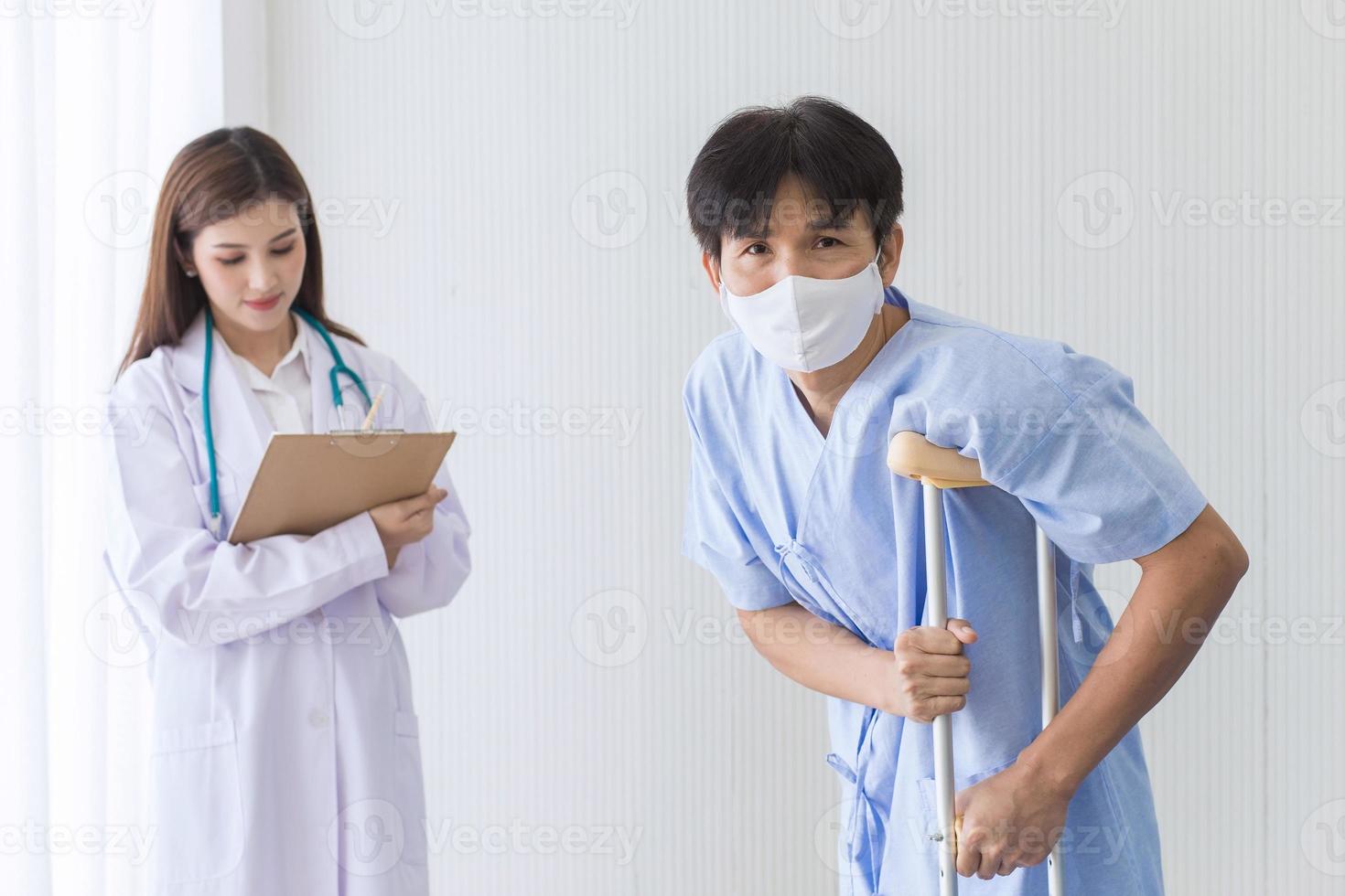 Aziatische vrouwelijke arts controleert het lopen van een mannelijke patiënt foto