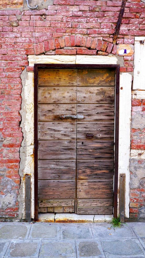 antieke houten deur en oude bakstenen muur in Venetië, Italië foto