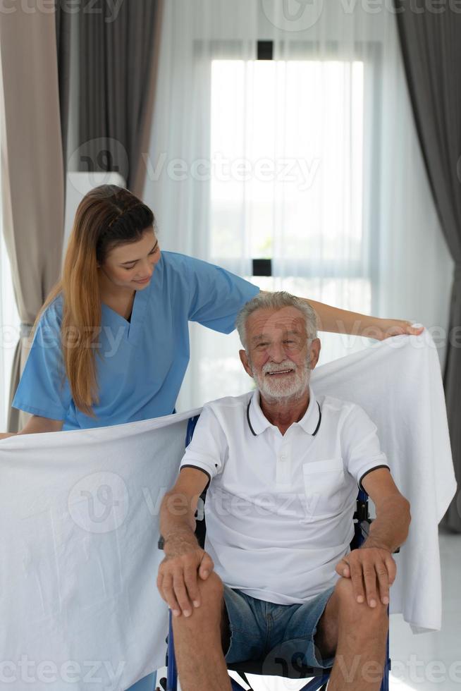 de dokter trekt een deken aan om zich op te warmen en praat met een oudere patiënt met een depressie. in de woonkamer van het huis foto