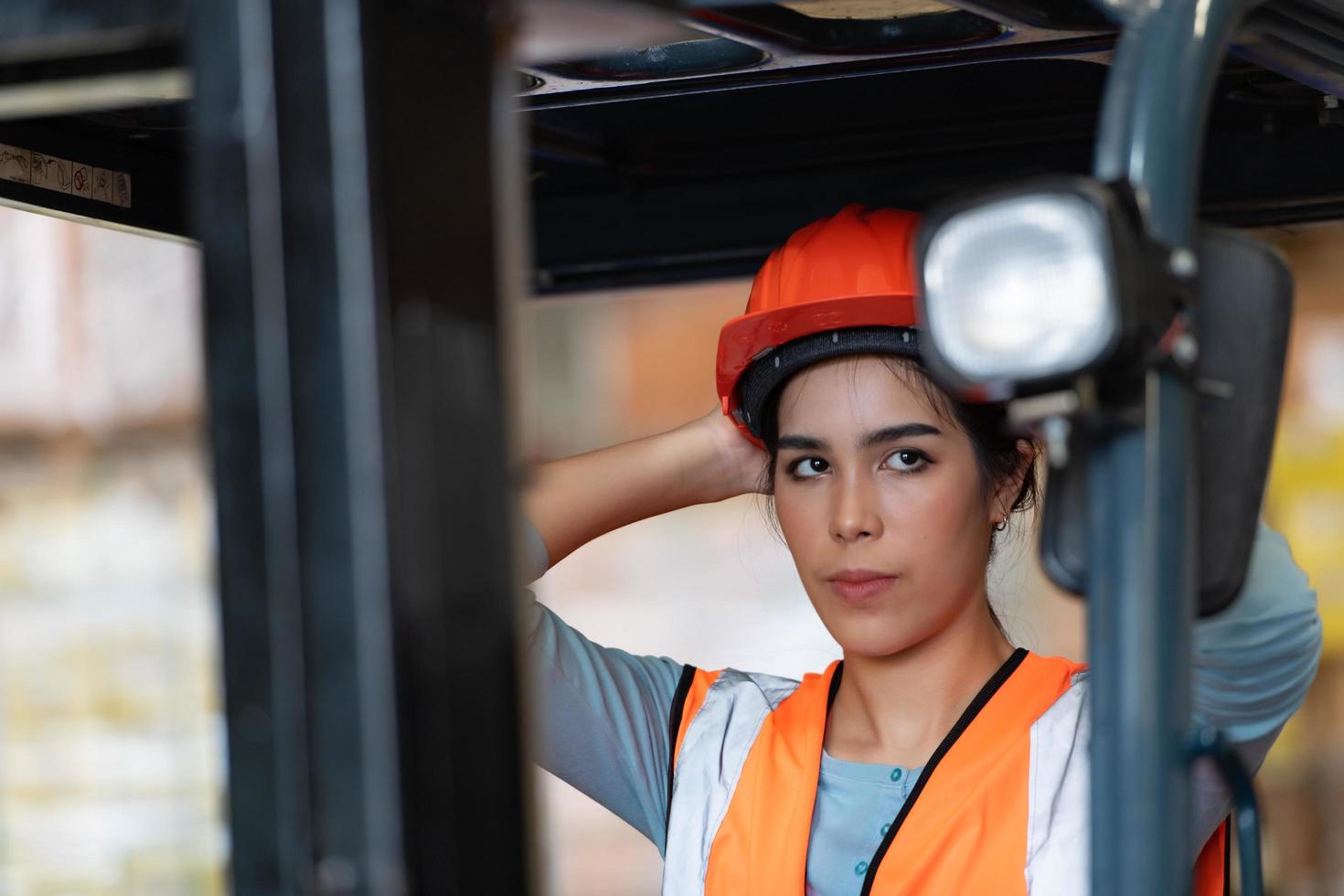 portret van een aziatische vrouw met een vorkheftruck die wordt gebruikt om zware voorwerpen in een magazijn op te tillen. foto