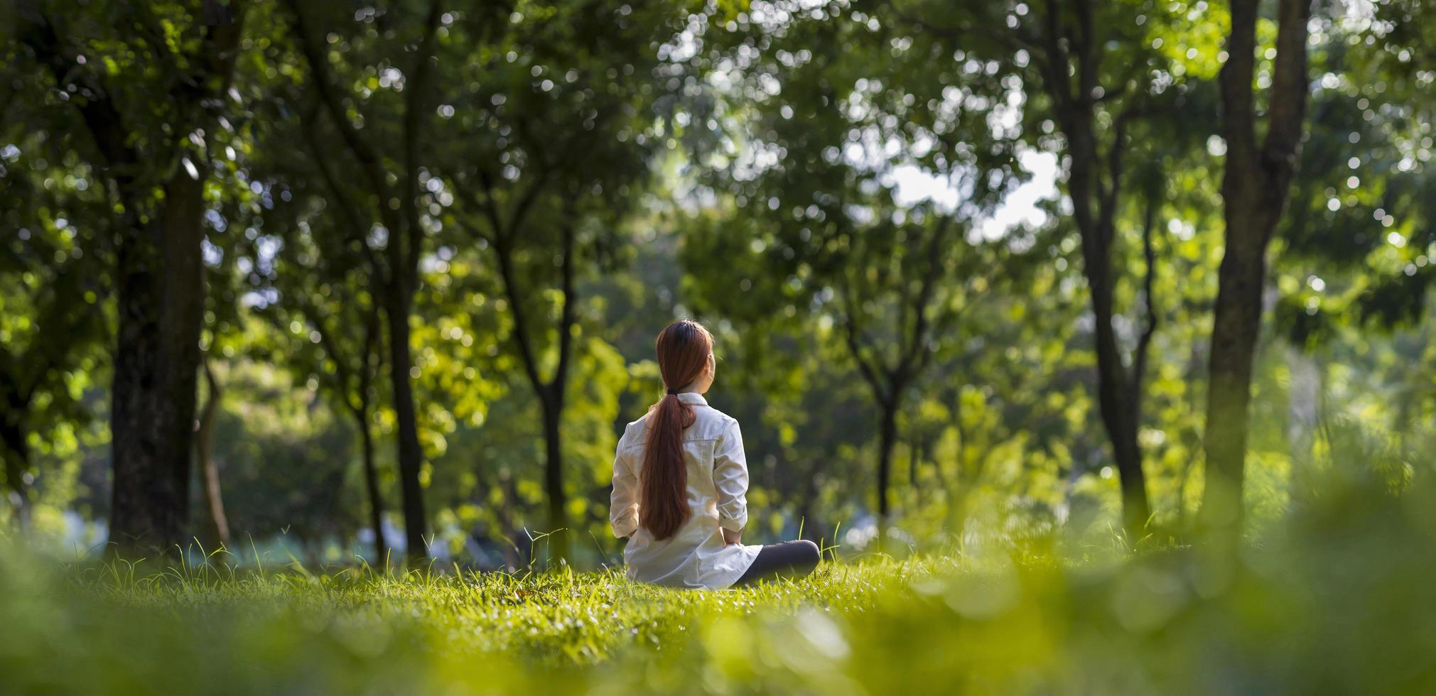 vrouw die ontspannen meditatie beoefent in het bos om geluk te bereiken vanuit innerlijke vrede wijsheid met een straal zonlicht voor een gezonde geest en ziel concept foto