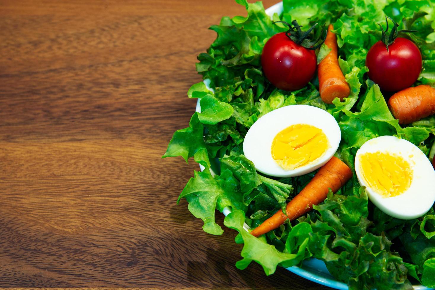 smakelijke verse mix groentesalade op witte schotel en houten plaat. foto