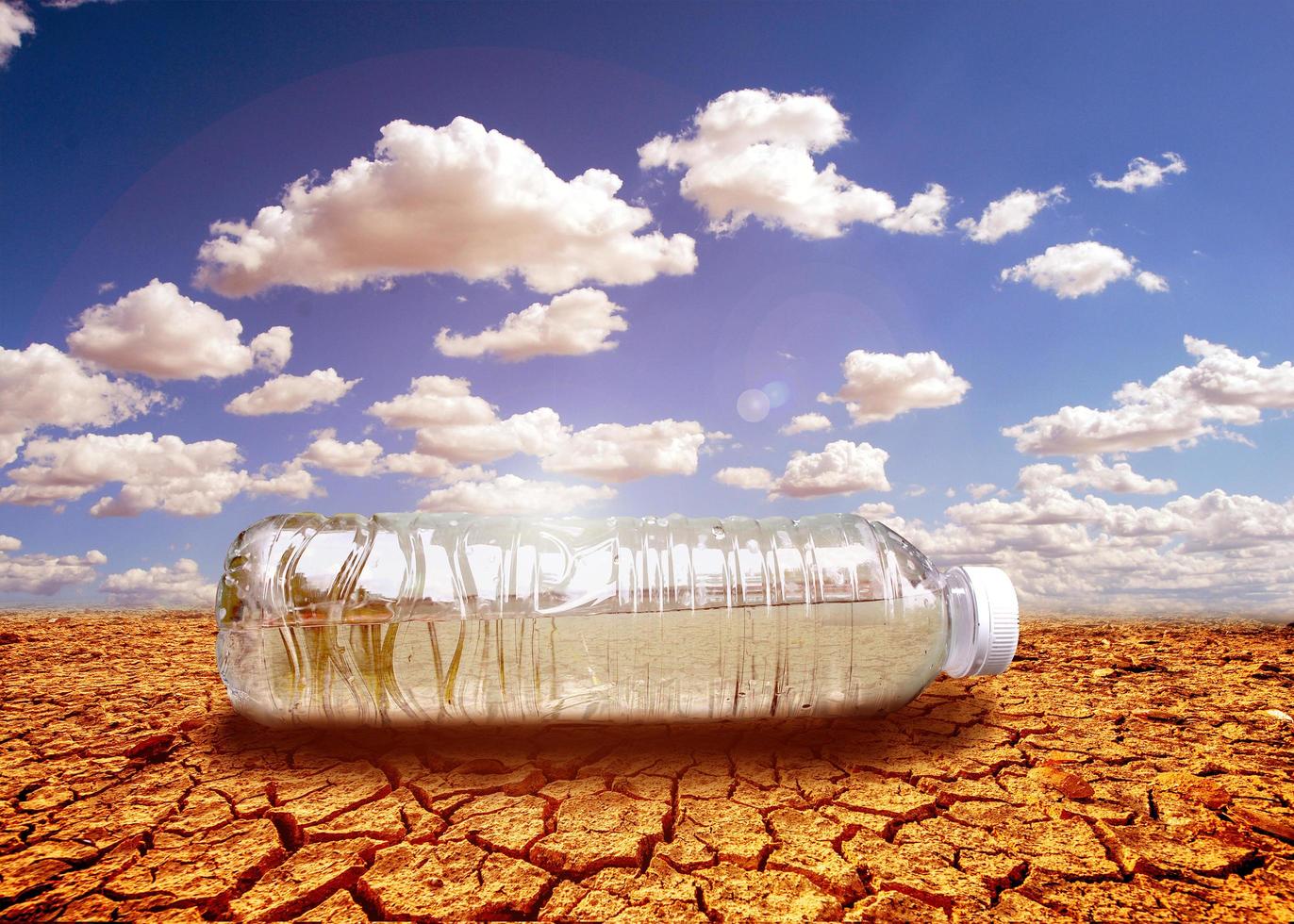concept van waterschaarste droogte als gevolg van de opwarming van de aarde. waterflessen geplaatst in gebieden met droogte en gebroken grond foto