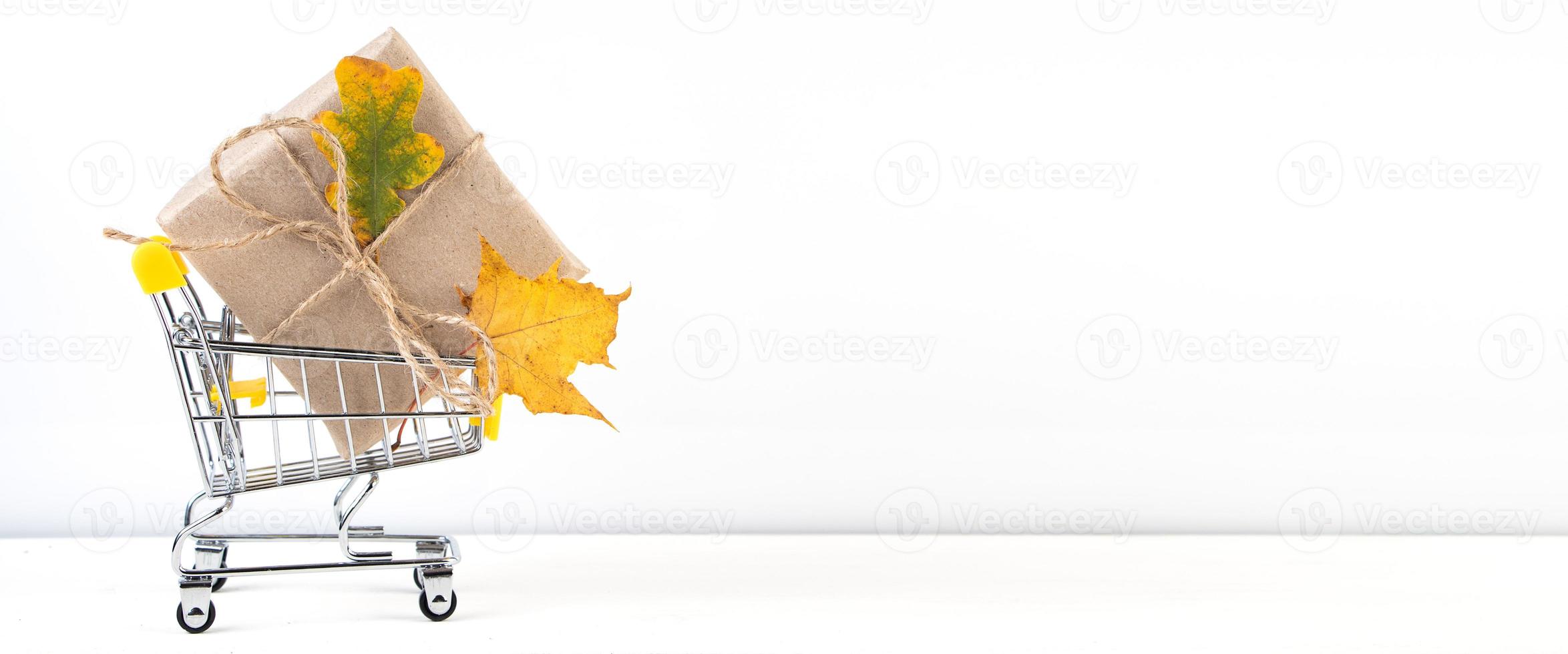 herfst verkoop. kortingsbanner voor reclame. winkelwagentje en gevallen gele bladeren op een witte achtergrond. foto