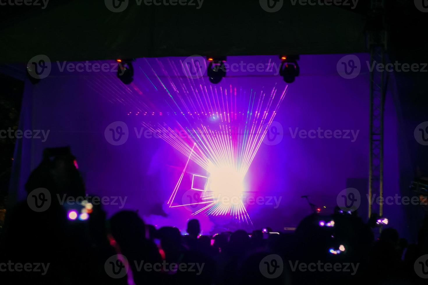 paarse laser neonstralen. menigte van mensen die kijken naar lasershow op straatfestival. foto