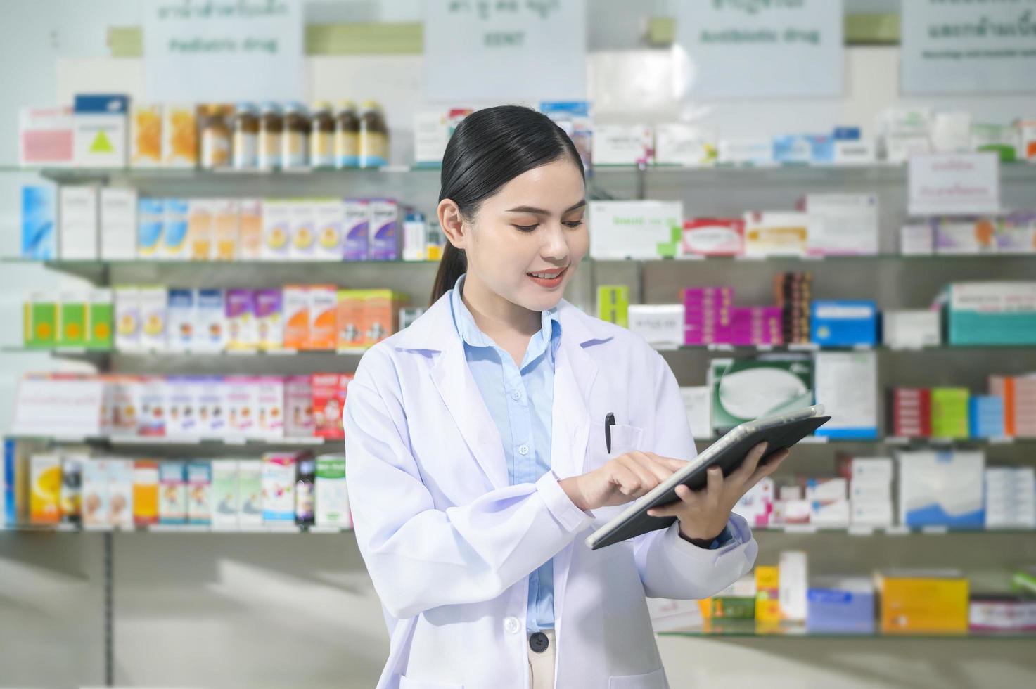 portret van vrouwelijke apotheker die tablet in een moderne apotheekdrogisterij gebruikt. foto