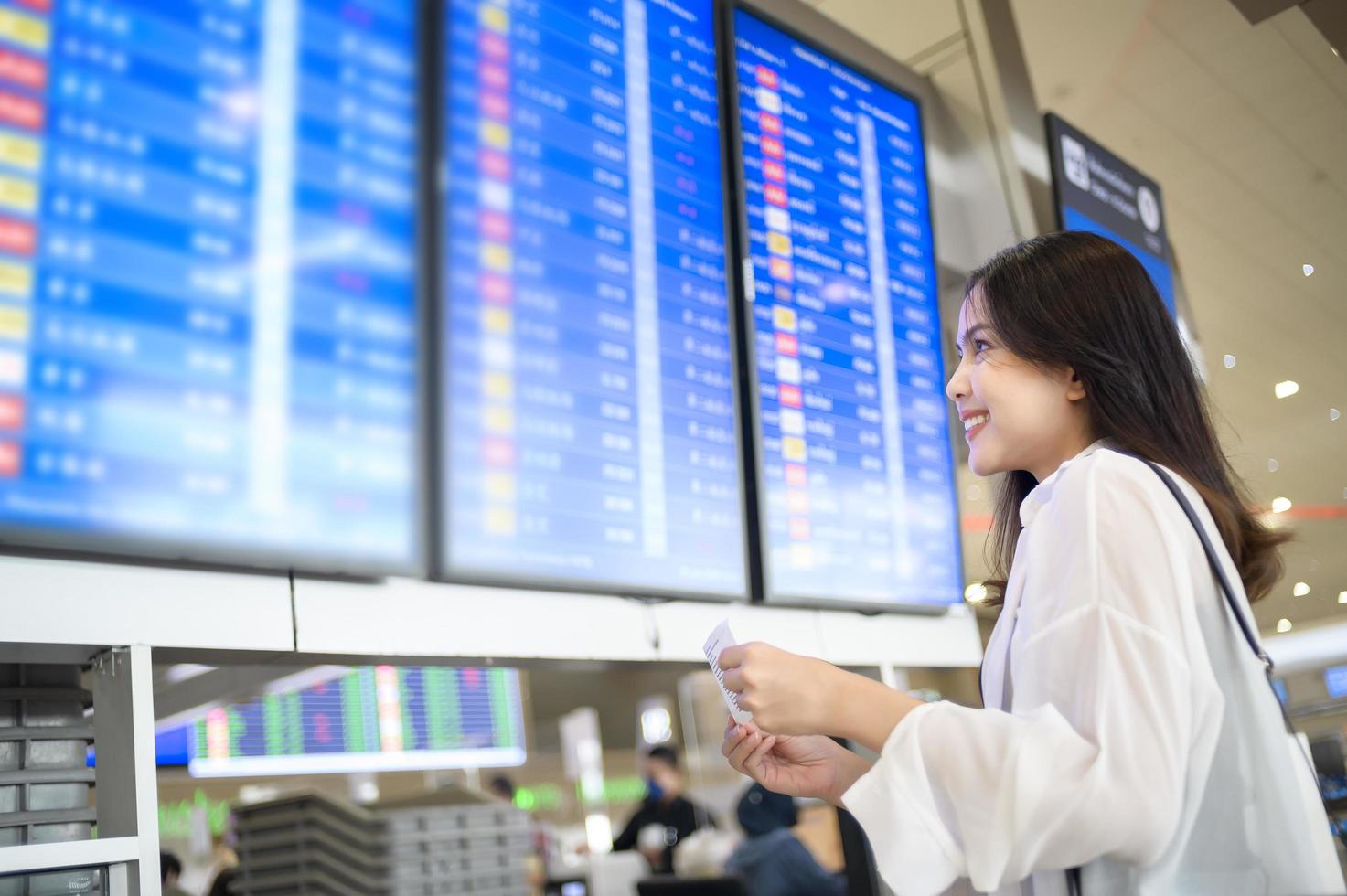 jonge vrouwelijke reiziger die koffers draagt op de internationale luchthaven, reizen, vakanties en reisconcept. foto