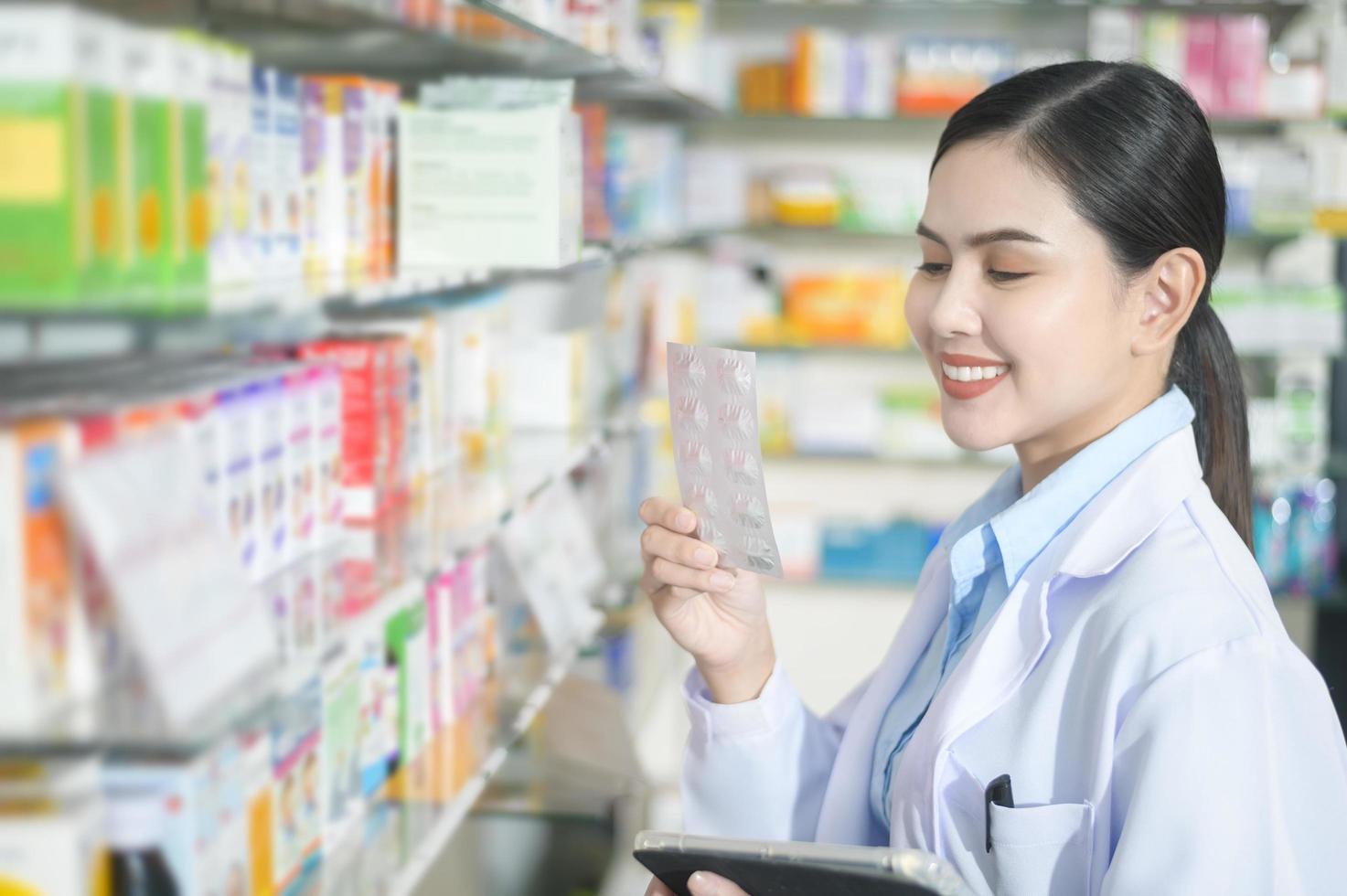 portret van vrouwelijke apotheker die tablet in een moderne apotheekdrogisterij gebruikt. foto