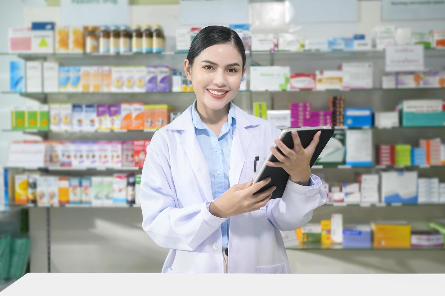 portret van vrouwelijke apotheker die tablet in een moderne apotheekdrogisterij gebruikt. foto