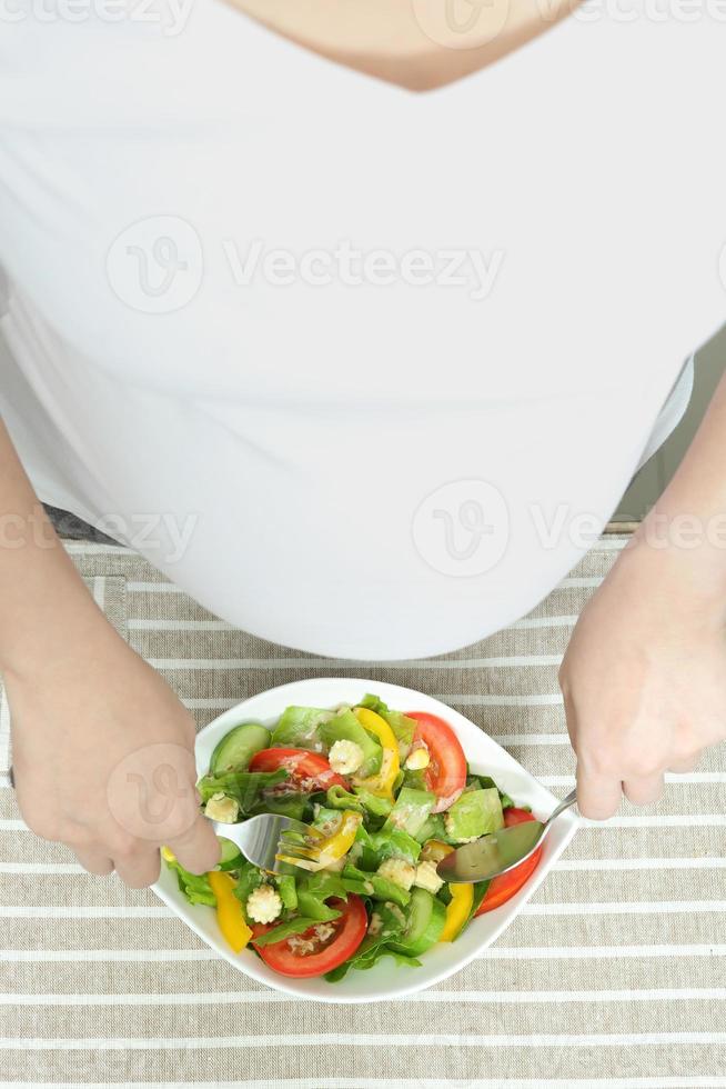 zwangere vrouw die groentesalade eet, gezond voor nieuw familieconcept foto