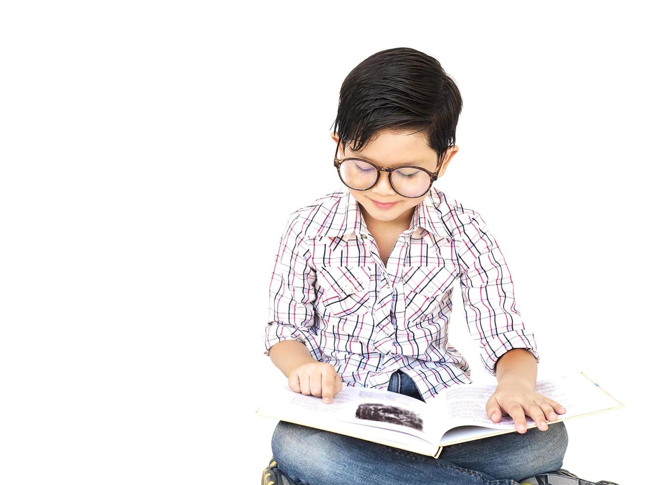 zeven jaar oude Aziatische jongen leest een boek opgewonden geïsoleerd over wit foto