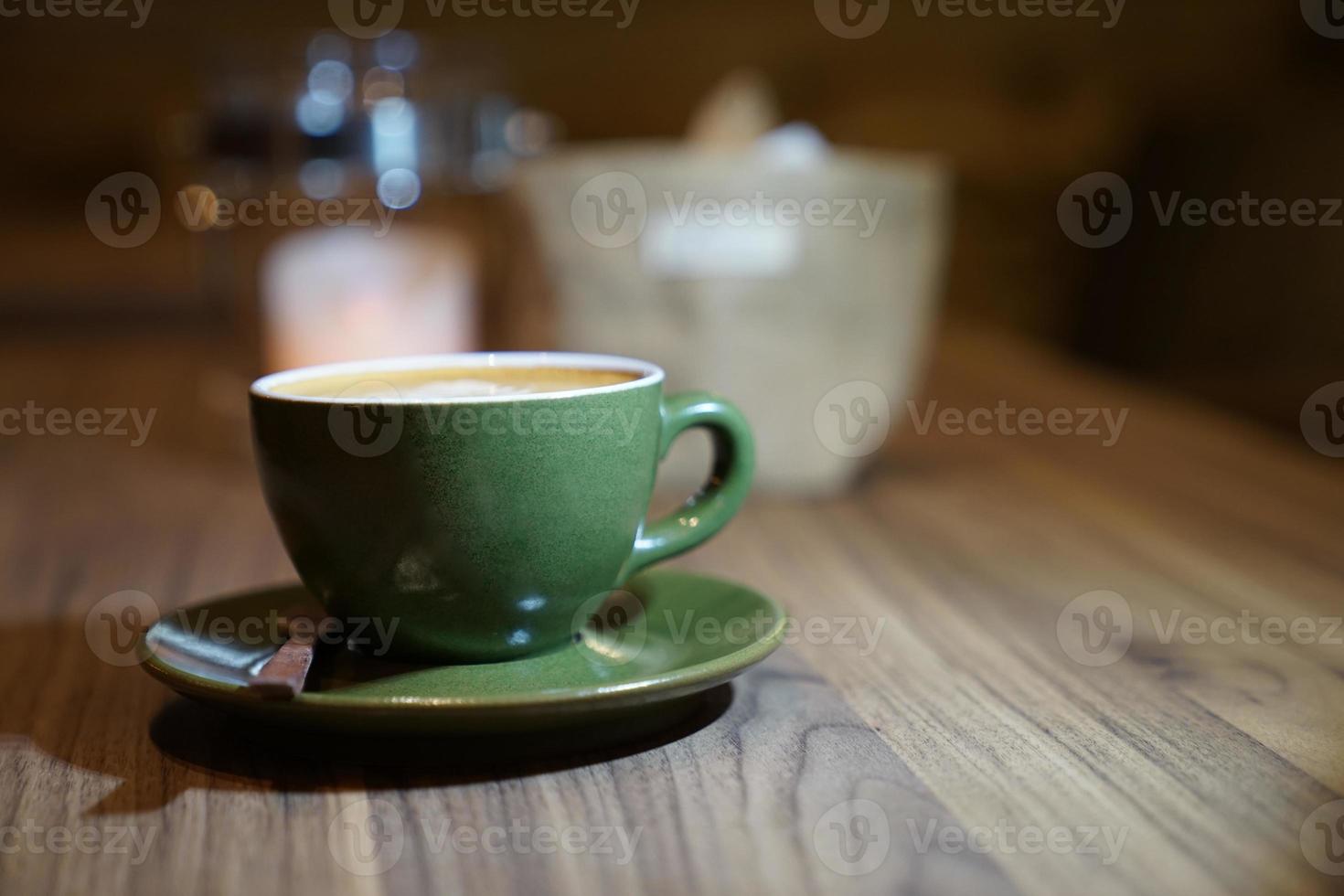 hete kunst latte in de groene kop op de houten tafel foto