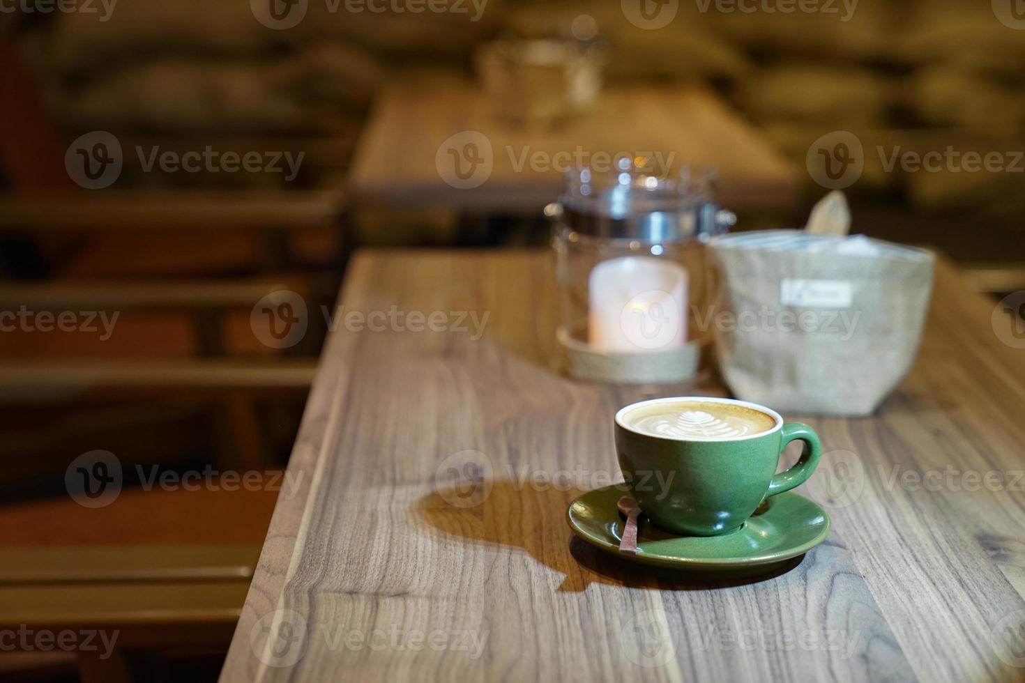 hete kunst latte in de groene kop op de houten tafel foto
