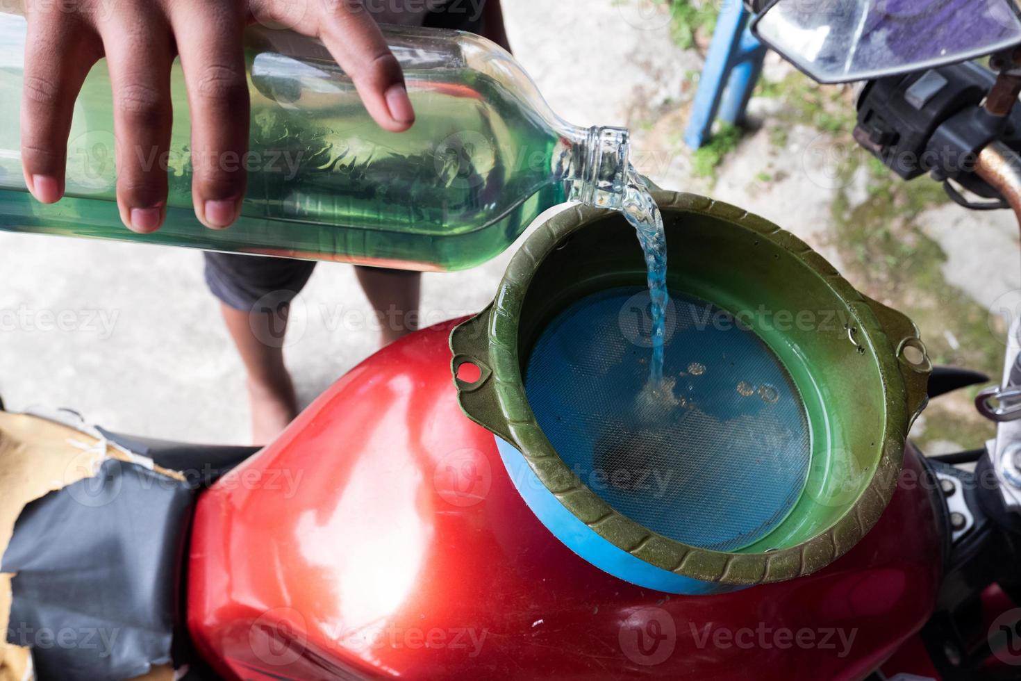 iemand giet pertalietbrandstof door een glazen fles voor motorfietsen, benzine die in de detailhandel wordt verkocht, is 1 liter foto