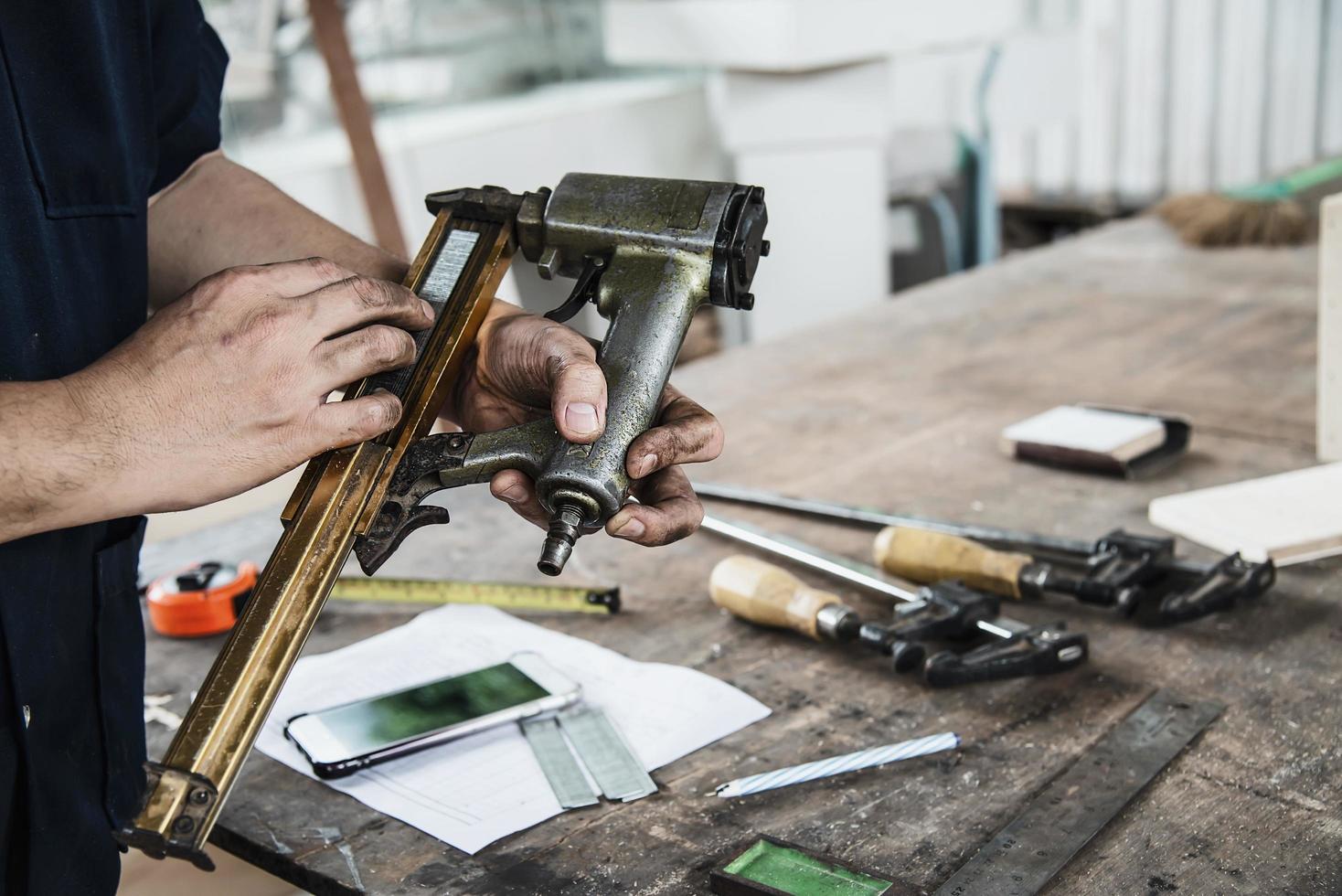 timmerman die luchtspijkerpistool gebruikt die houten meubelwerk doet foto