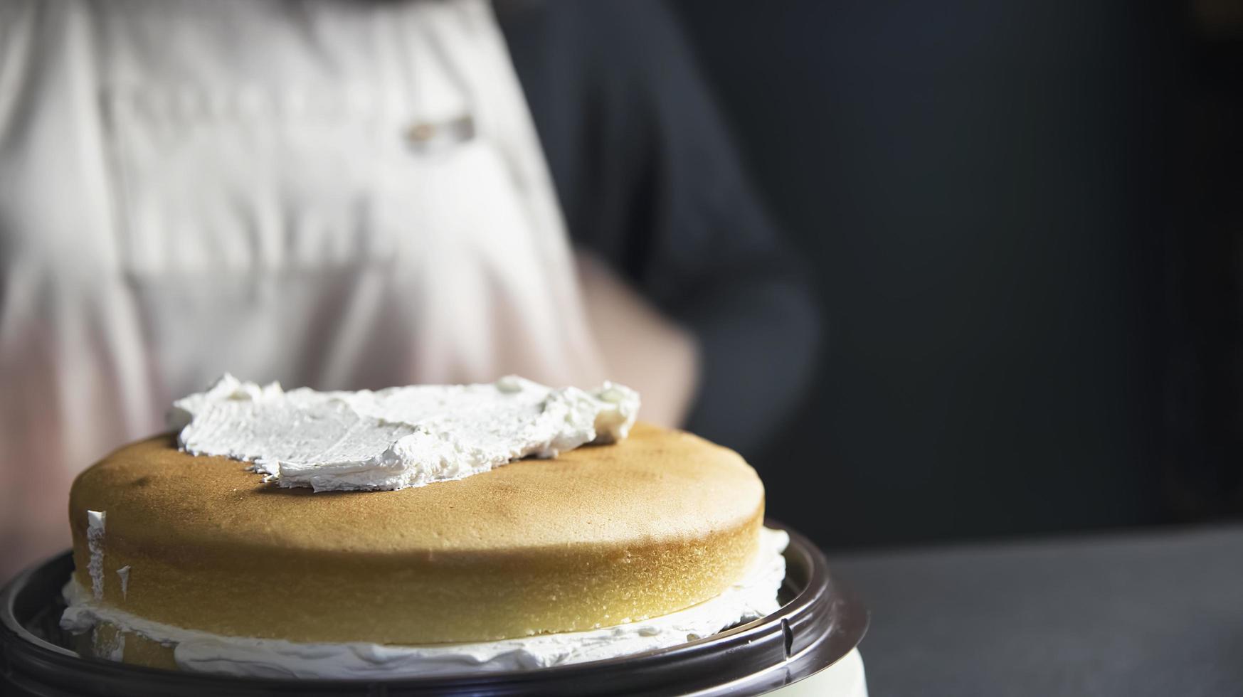 dame die cake maakt die room zet met behulp van spatel - zelfgemaakte bakkerij kookconcept foto