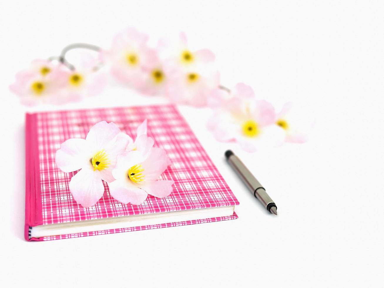 zoet roze dagboek met pen en kunstbloem, selectief gefocust en geïsoleerd over wit foto