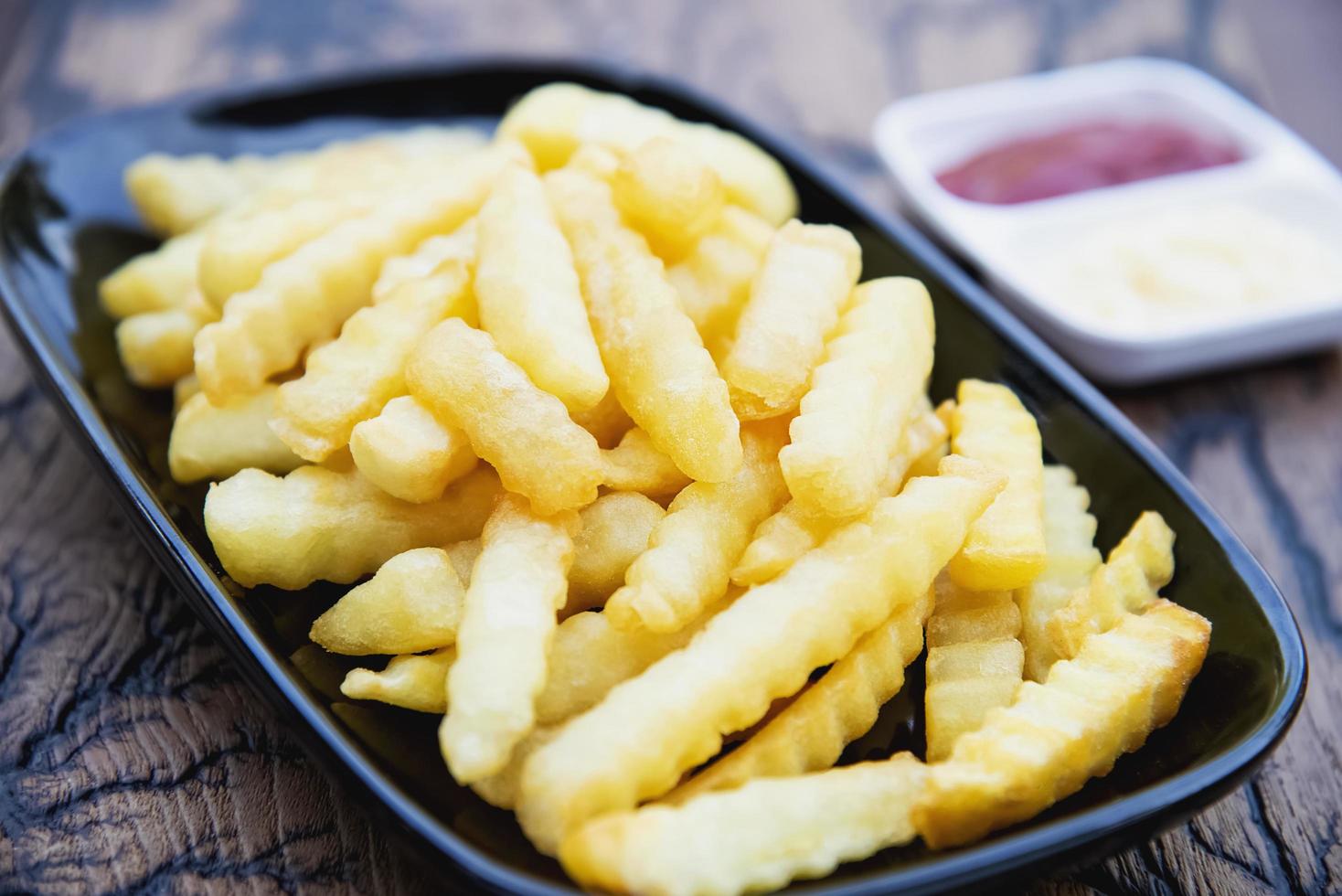 zijaanzicht van frietjes met sauzen op houten plaat foto