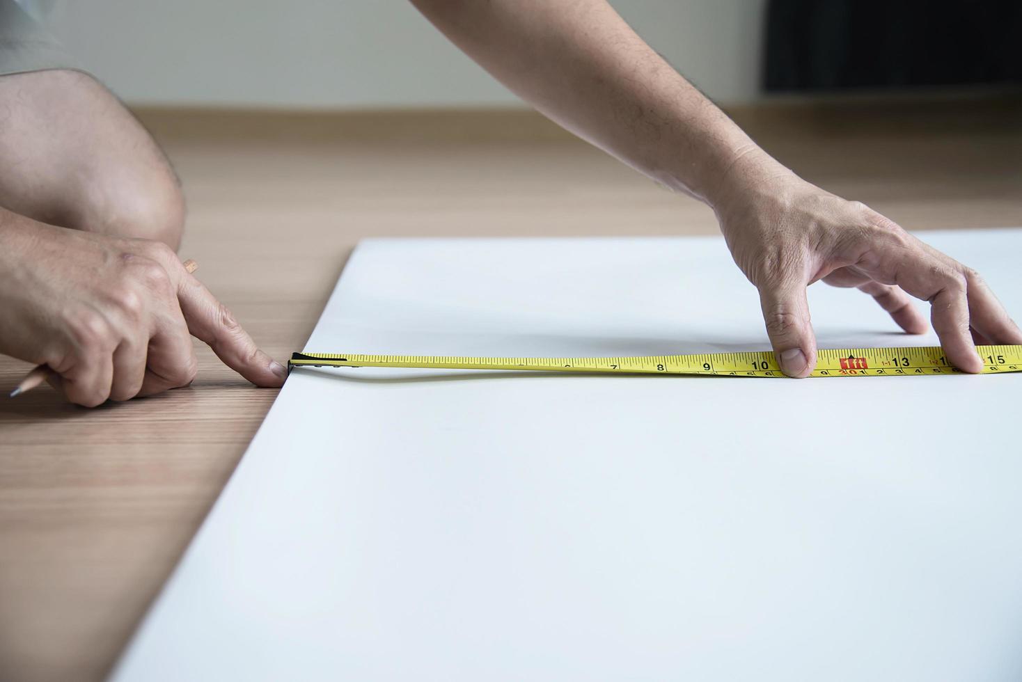 man met behulp van maatregel handgereedschap doet behang snijden werk in huis bouwplaats, mensen met handgereedschap object concept foto