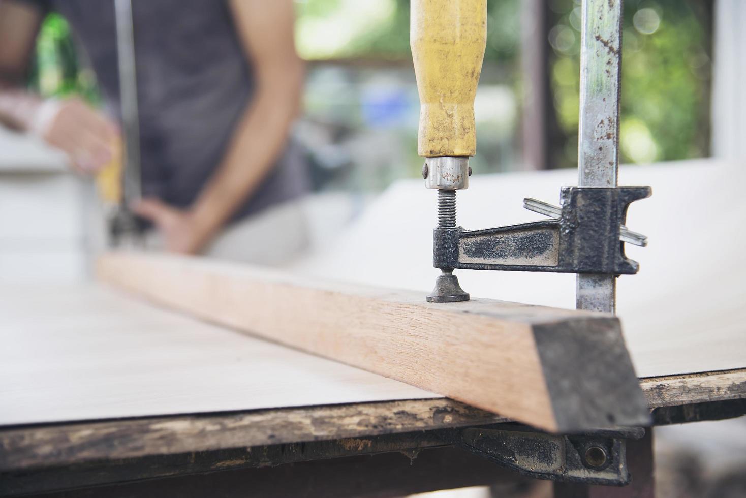 timmerman die houtwerk doet met behulp van klemmend handgereedschap foto