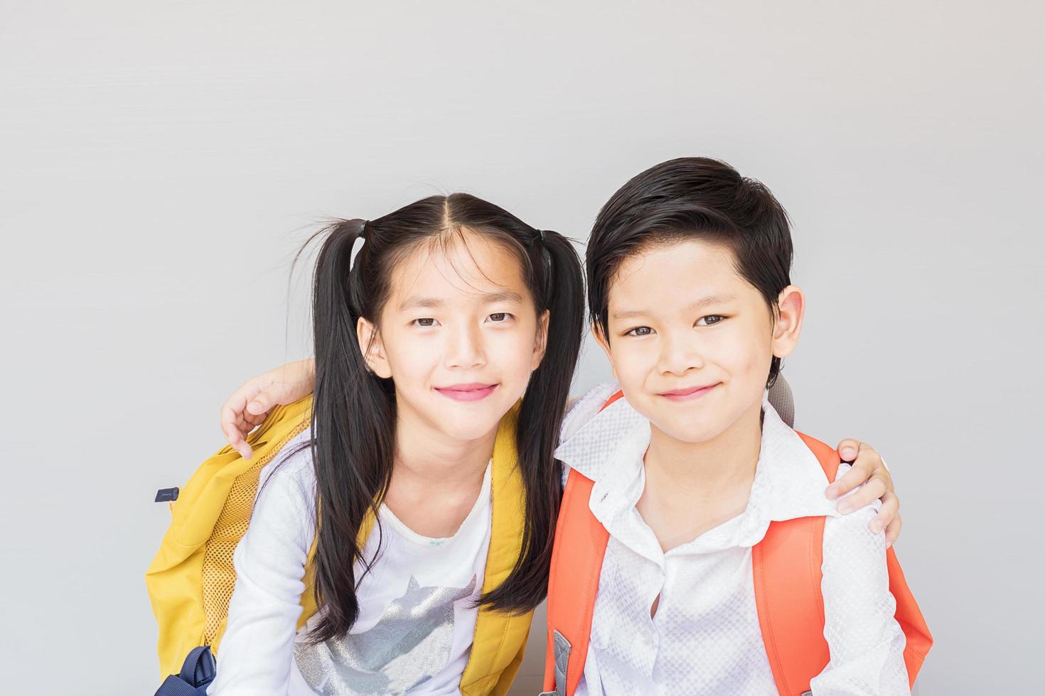 mooie Aziatische paar schoolkinderen, 7 en 10 jaar oud, over grijze achtergrond foto