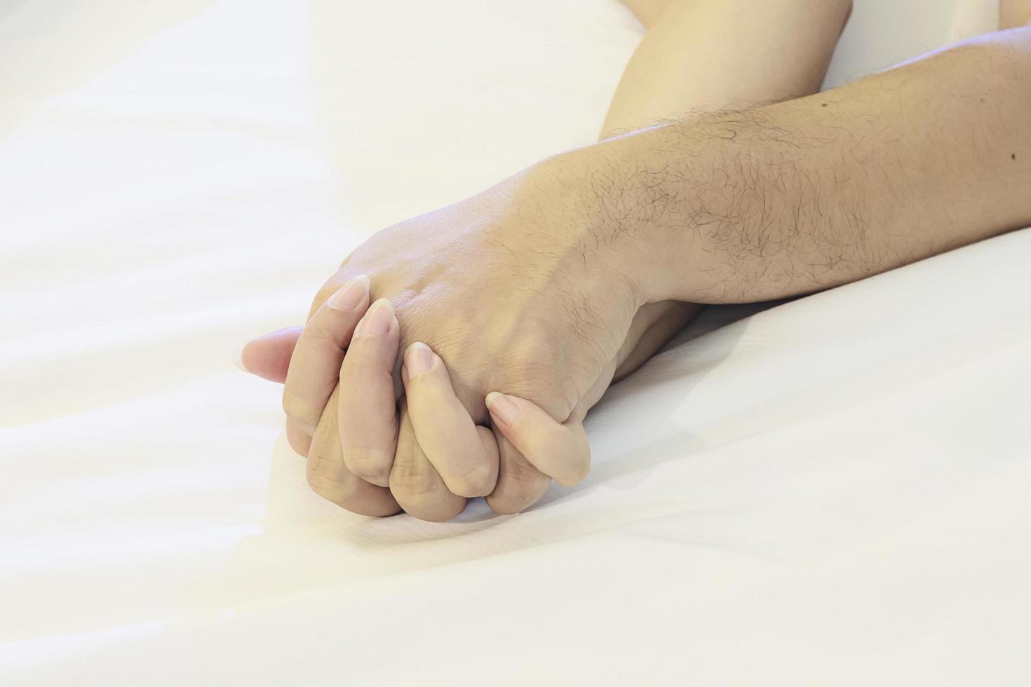 man met vrouw hand op wit bed, paar seksuele concept foto