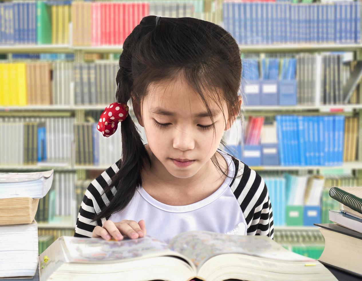 Aziatisch meisje leest boek in een bibliotheek foto