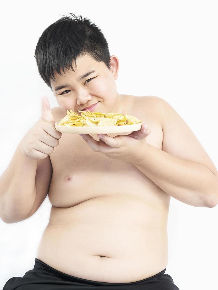 dikke jongen eet vrolijk chips. foto is gericht op zijn gezicht.