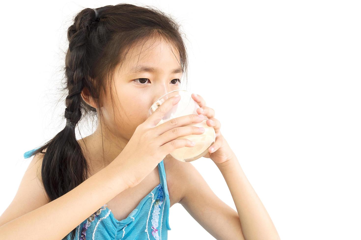 Aziatisch meisje drinkt een glas melk op een witte achtergrond foto