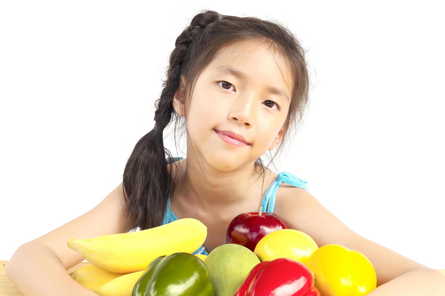 Aziatische gezonde gril die gelukkige uitdrukking met verscheidenheids kleurrijk fruit en groente toont op witte achtergrond foto