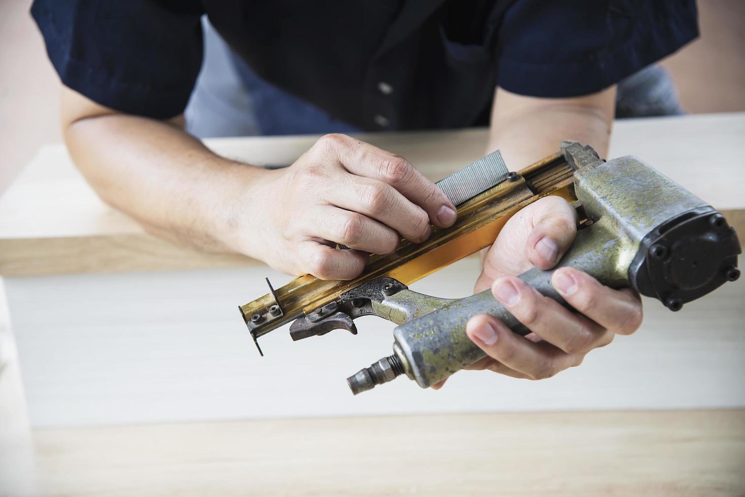 timmerman die luchtspijkerpistool gebruikt die houten meubelwerk doet foto