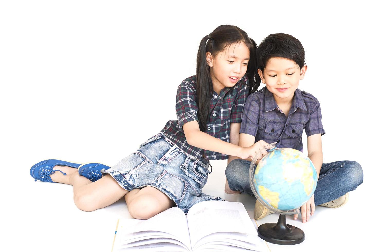 Aziatische 7 en 10 jaar jongen en meisje studeren wereldkaart, geïsoleerd op witte achtergrond foto