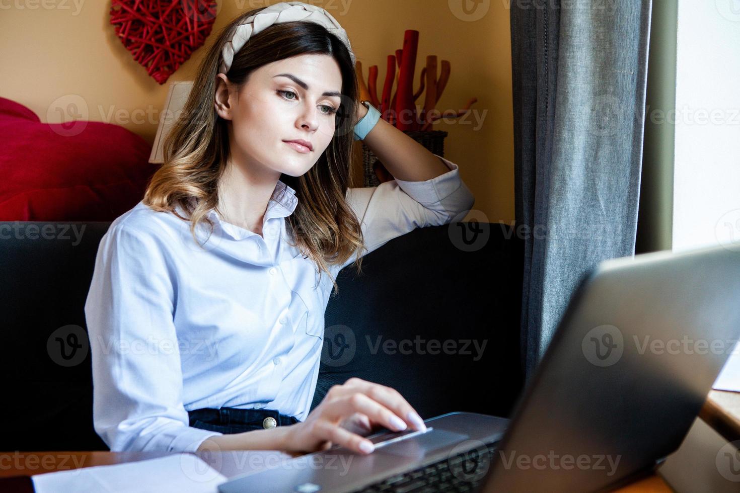 het meisje werkt op de computer in een café. student online leren. blogger. jonge blanke vrouwelijke schrijver toetsenborden op laptop. aantrekkelijke zakenvrouw met behulp van draagbare computer tijdens een pauze. foto