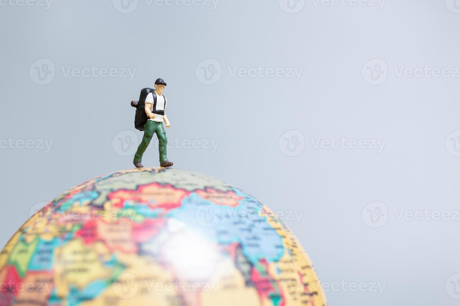 reizigers in het klein, staande op de wereldbol en op weg naar hun bestemming, foto