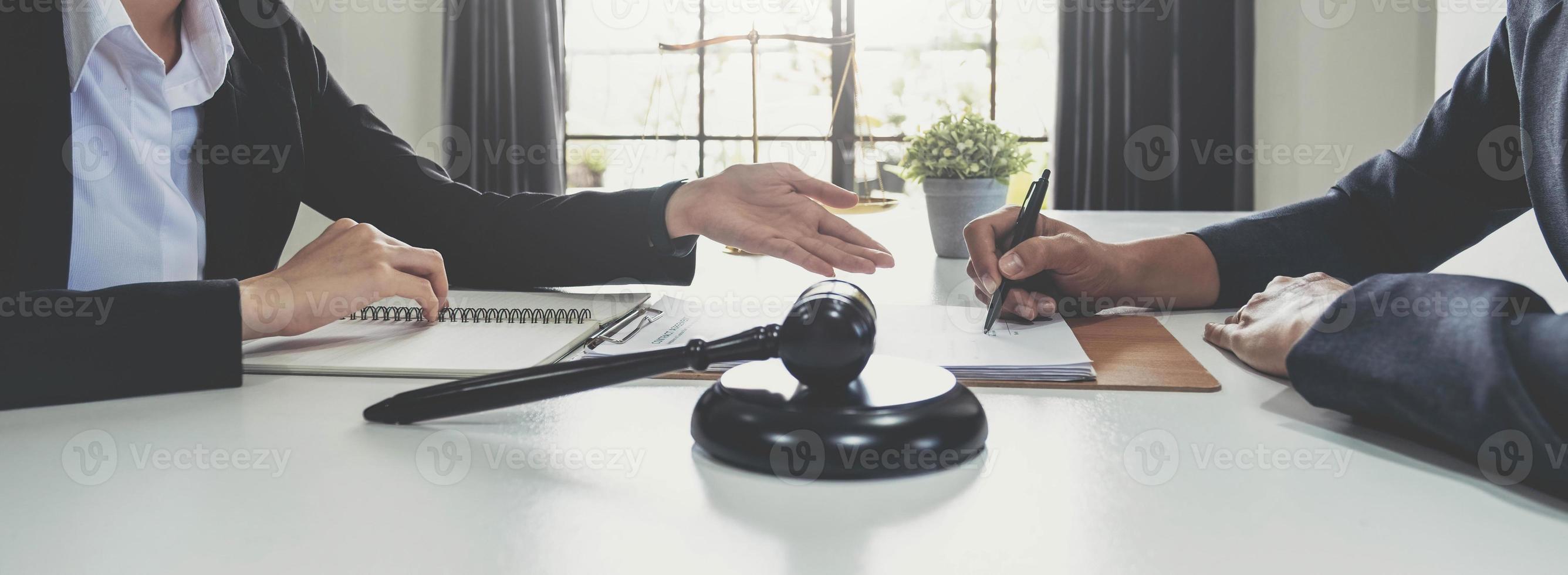 zakenvrouw en advocaten bespreken contractpapieren met koperen schaal op houten bureau in kantoor. wet, juridische diensten, advies, rechtvaardigheidsconcept. foto