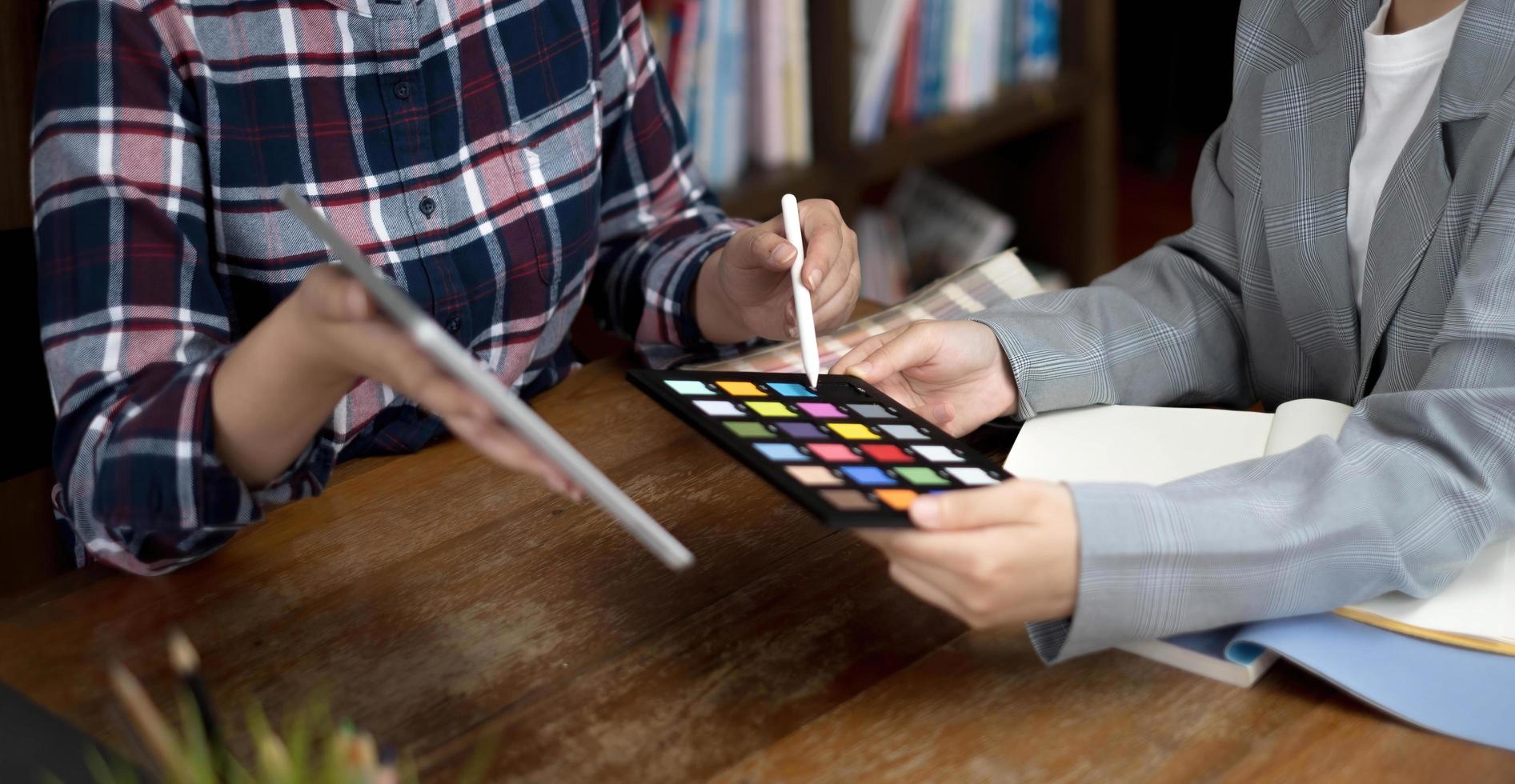 twee kunstenaars die aan tablet werken, kleur papiertint op werkruimte op kantoor foto