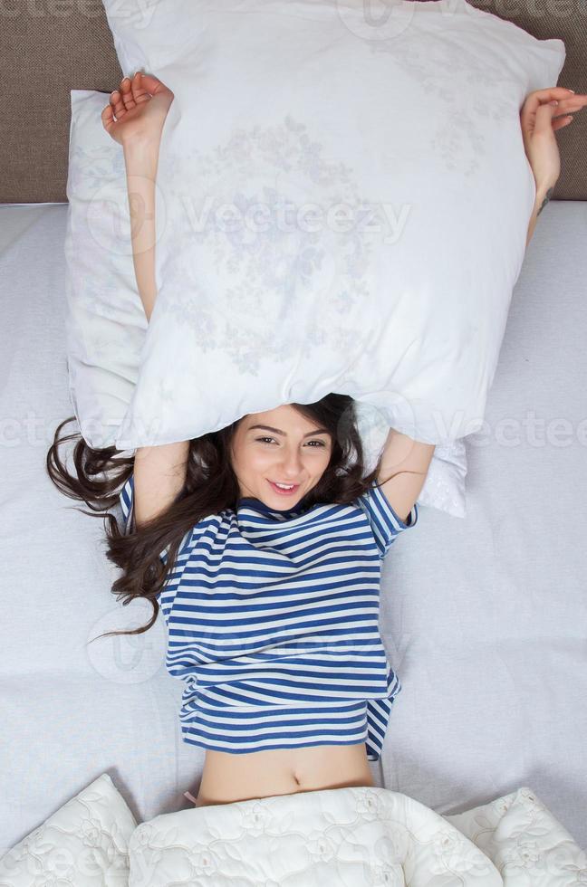 meisje slaapt thuis in een wit bed. jonge vrouw slapen in nachtkleding op het witte linnen in bed thuis, bovenaanzicht. foto