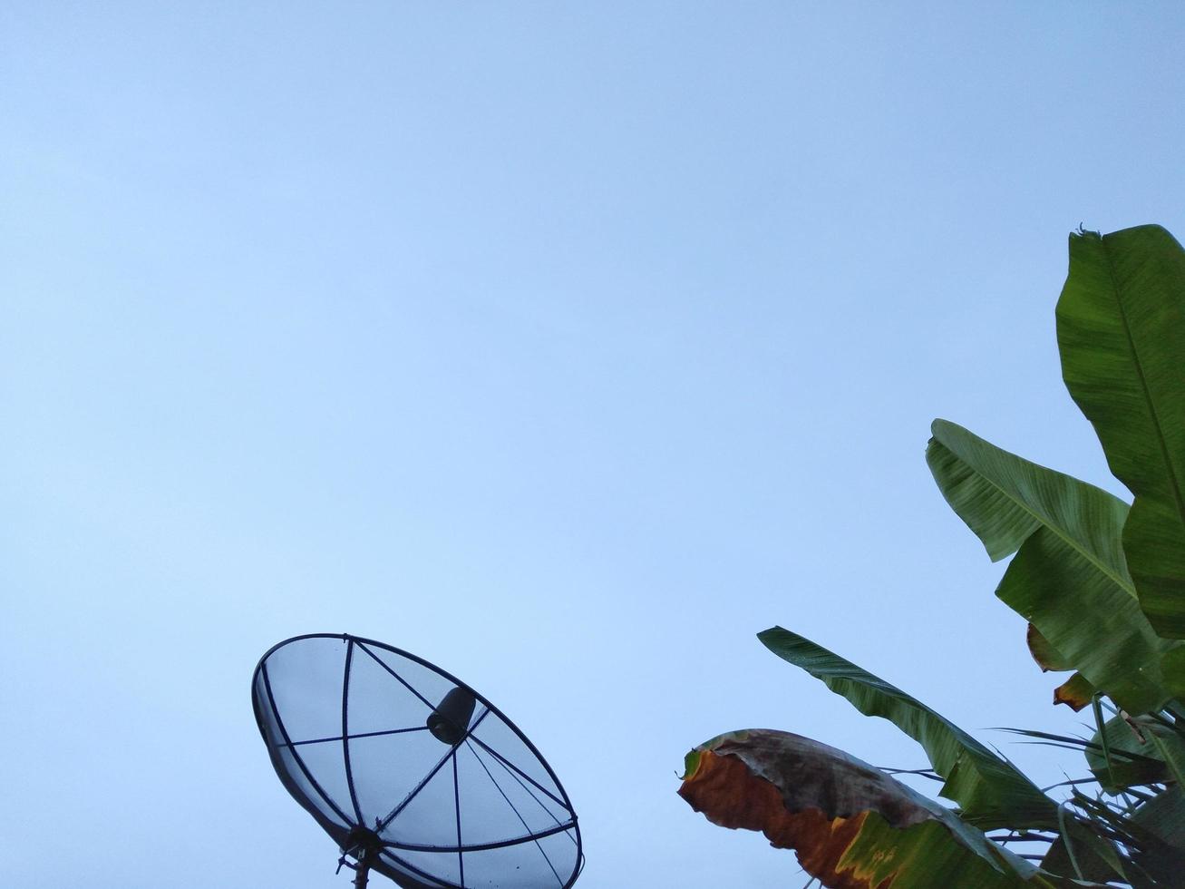 zwarte schotelantenne op het dak van het huis bewolkte lucht op een dag met slecht weer foto