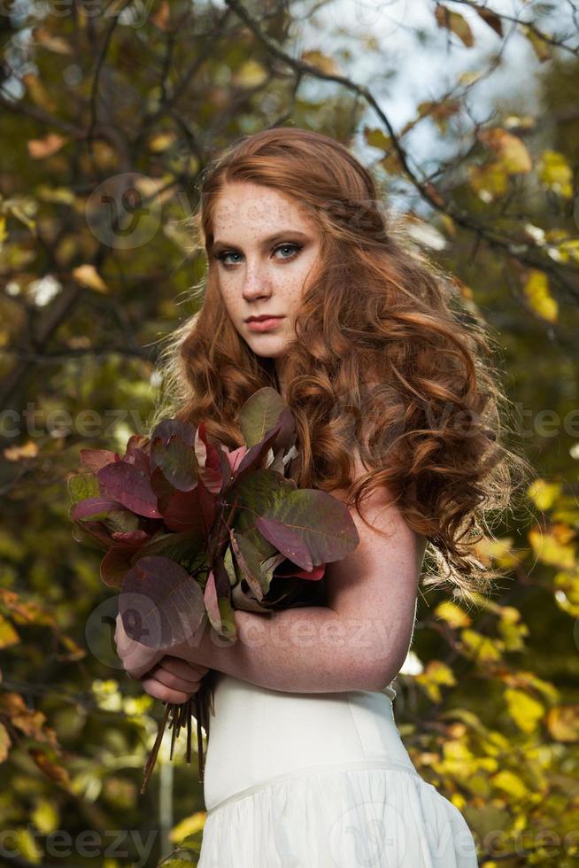jonge vrouw met een bos gele esdoornbladeren. herfst portret van jonge vrouw. roodharig meisje in herfstbos foto