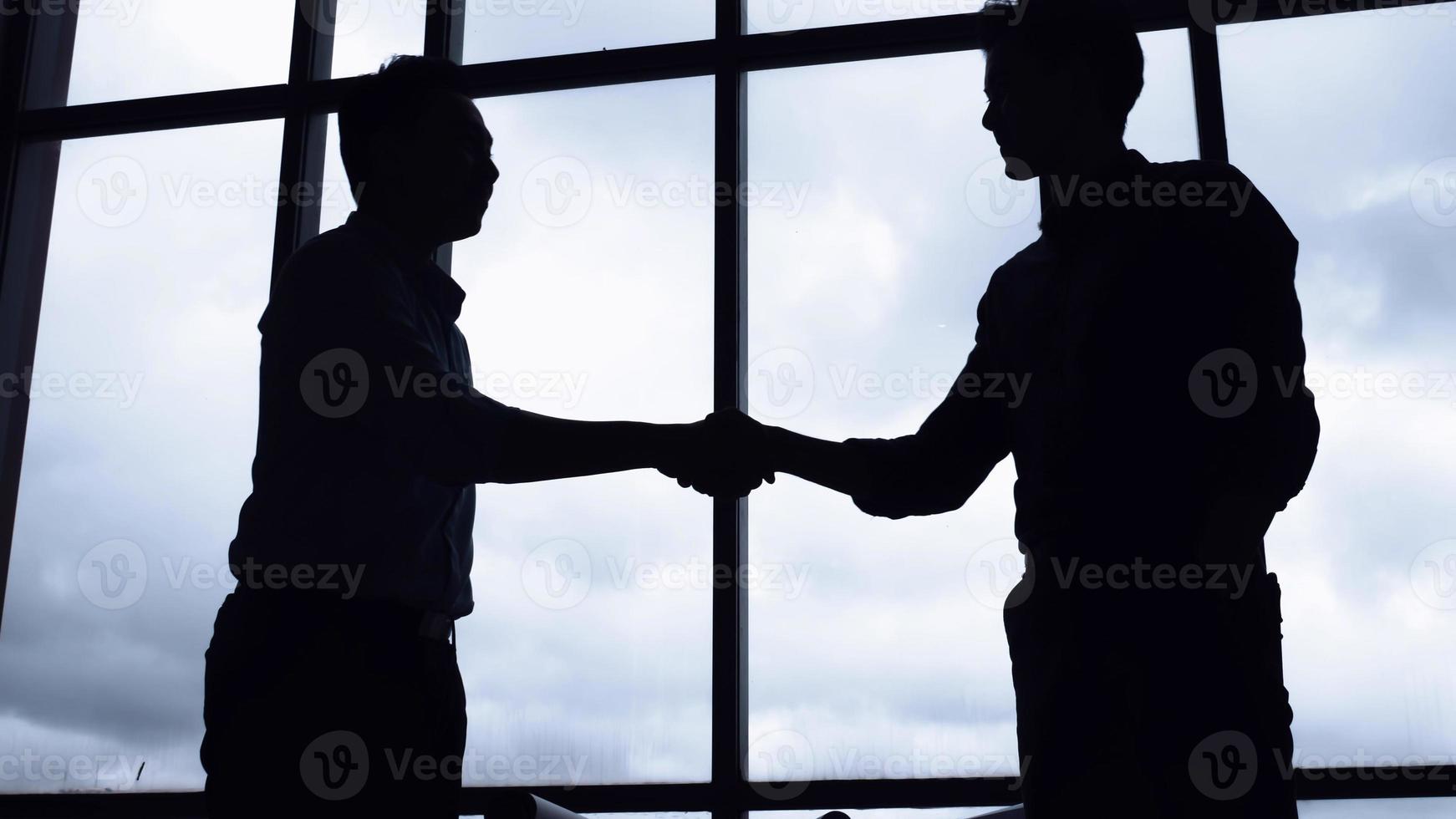 twee succesvolle zakenlieden die elkaar de hand schudden op kantoor. foto