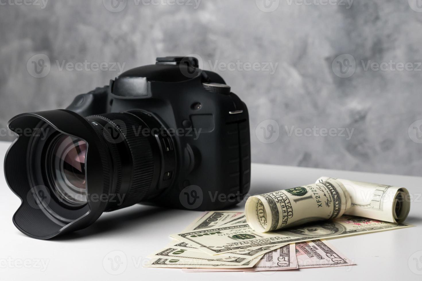 een zwarte digitale camera en bankbiljetten op een witte tafel met grunge achtergrond. foto