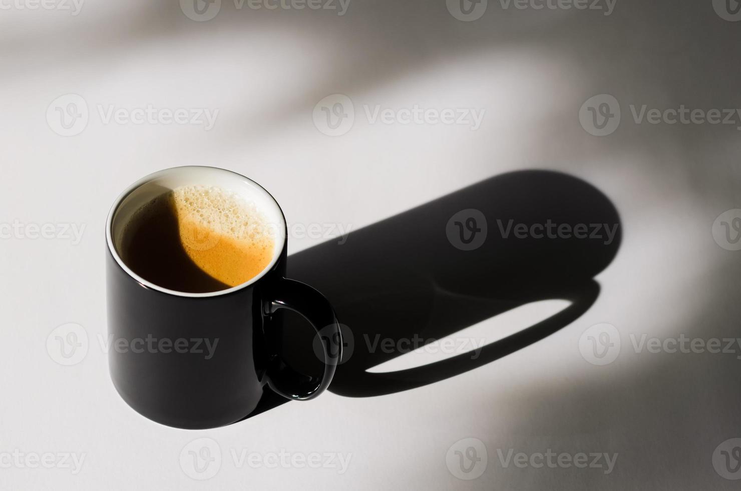 een zwarte kop warme koffie op een witte tafel met schaduw foto